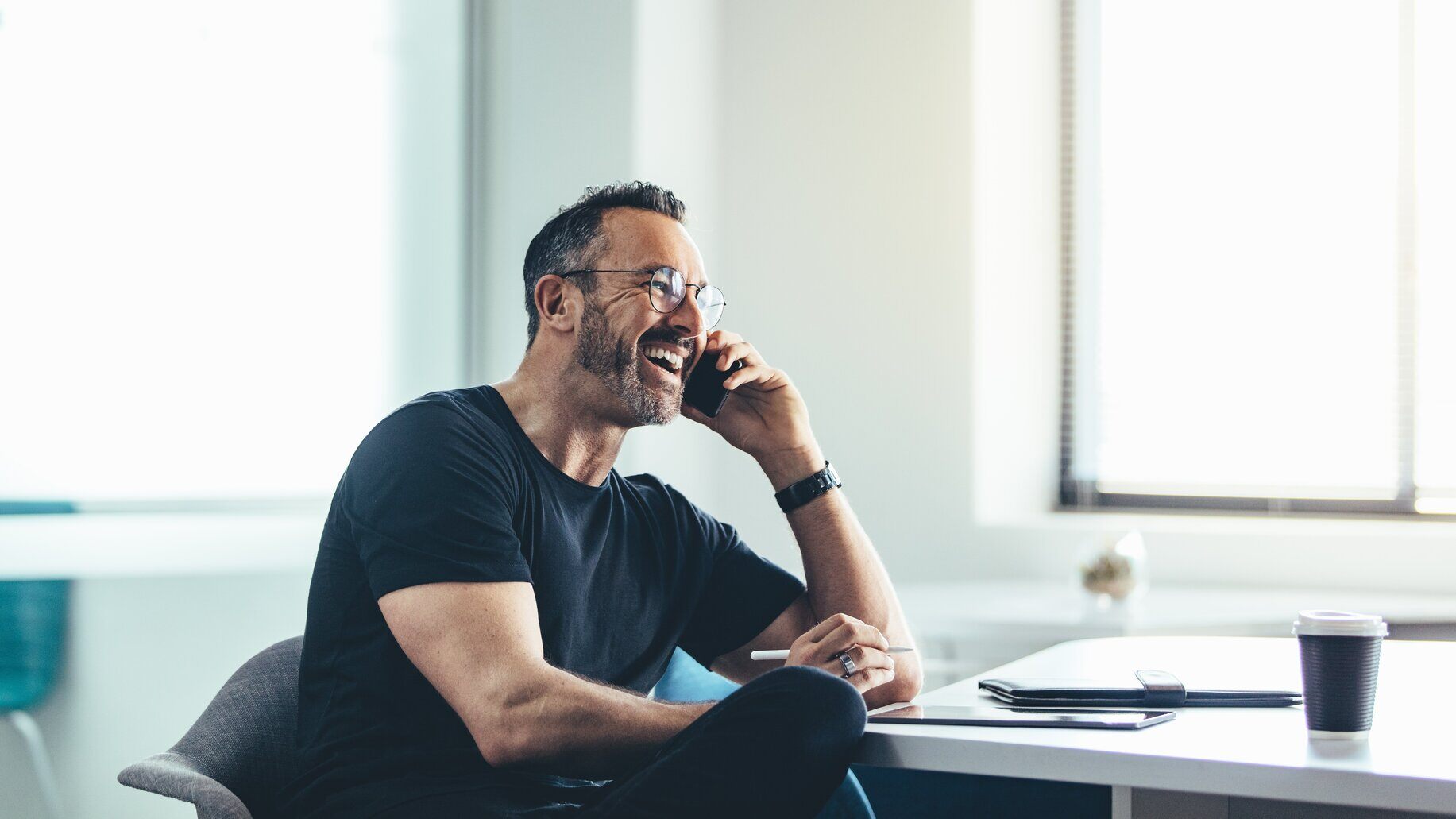 Glad man snakker i telefon på sin arbejdsplads