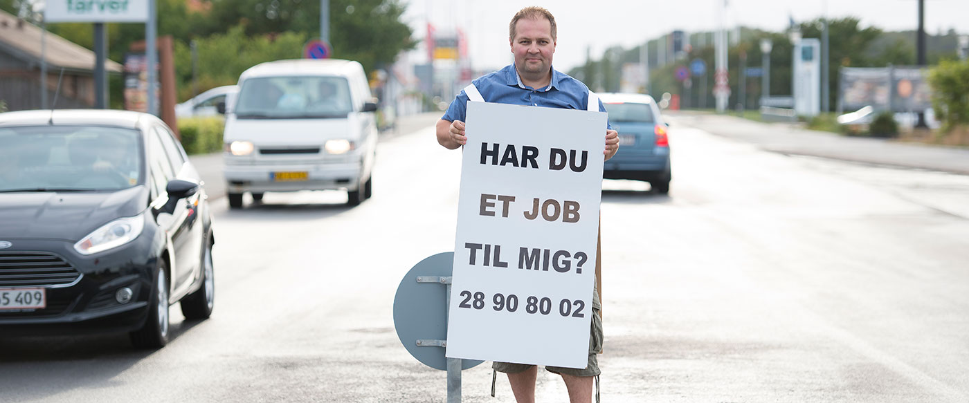 Mand står med skilt som han bruger til at søge job